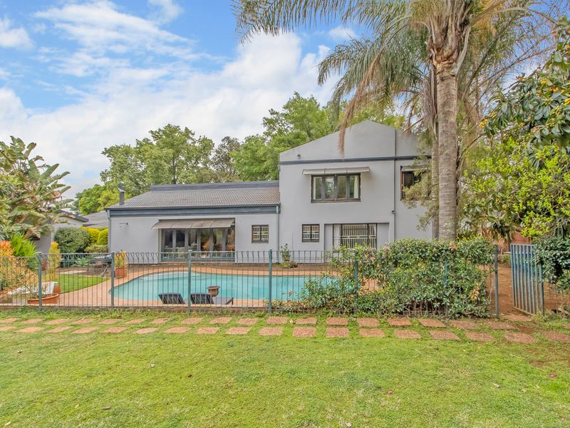 Rear view of the property featuring a swimming pool, paved surround, metal fencing, and a well-maintained garden area.