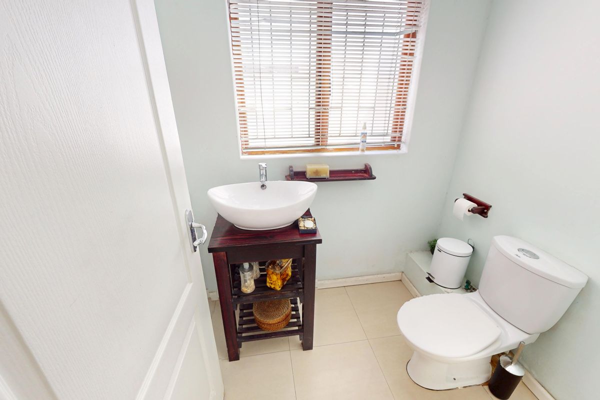 A compact bathroom featuring a vessel sink on a wooden vanity, a standard toilet, and tiled flooring with natural light from a window.