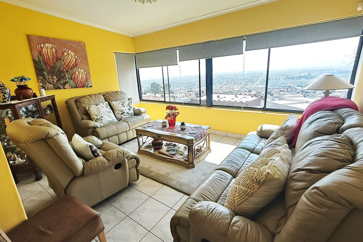 A bright living room featuring tiled floors and expansive windows offering panoramic views, providing a comfortable and well-lit space.