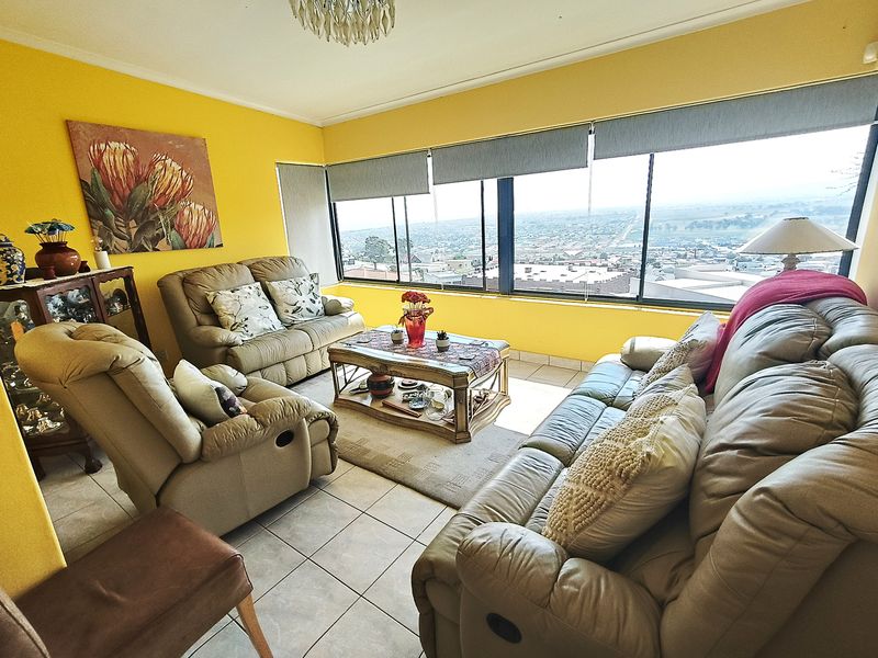 A bright living room featuring tiled floors and expansive windows offering panoramic views, providing a comfortable and well-lit space.