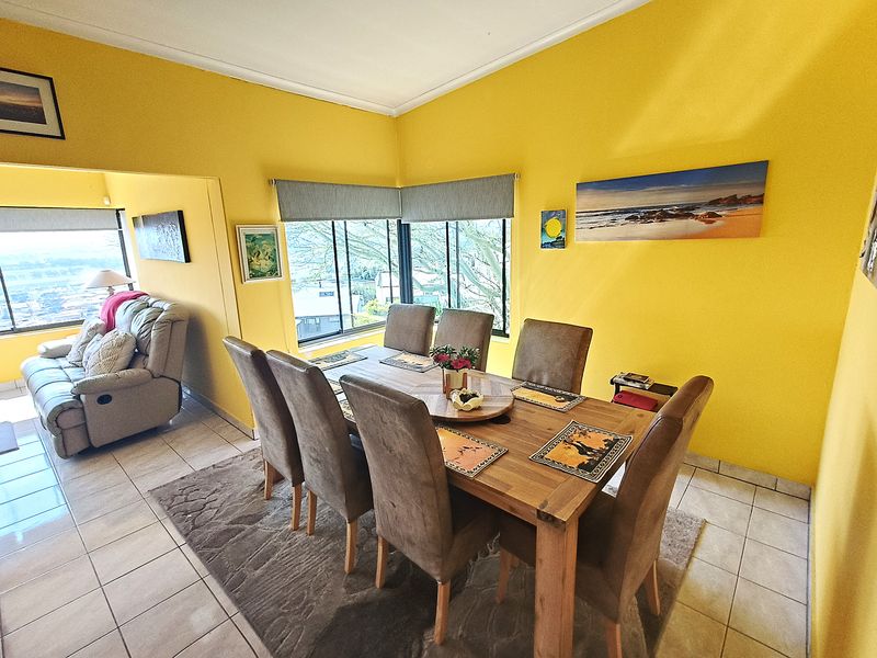 A dining area featuring tiled flooring and corner windows with roller blinds, offering an open-plan connection to the adjacent living space.
