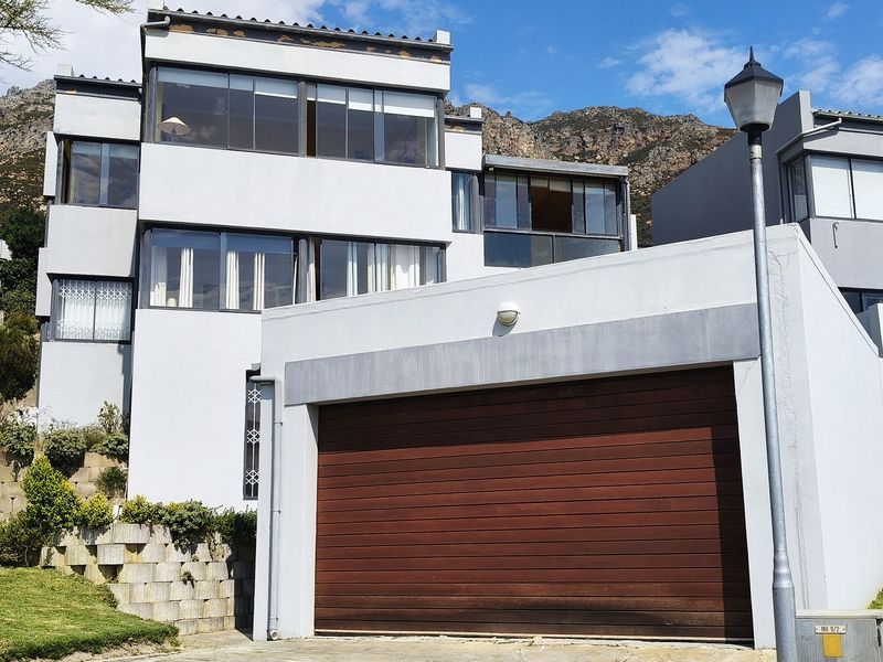 Front elevation of a multi-story residential property featuring a large garage door, modern architectural lines, and mountain views.