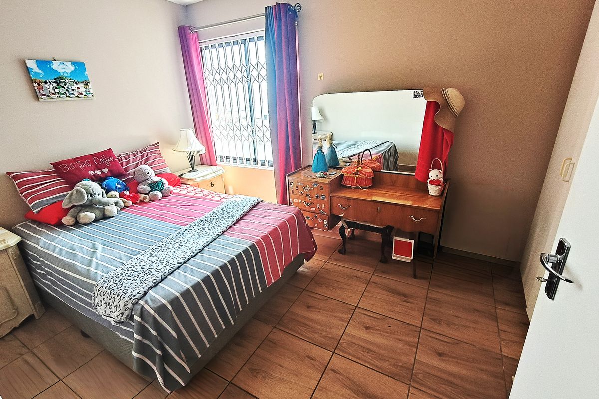 A bedroom featuring tiled flooring and a window fitted with a security gate.