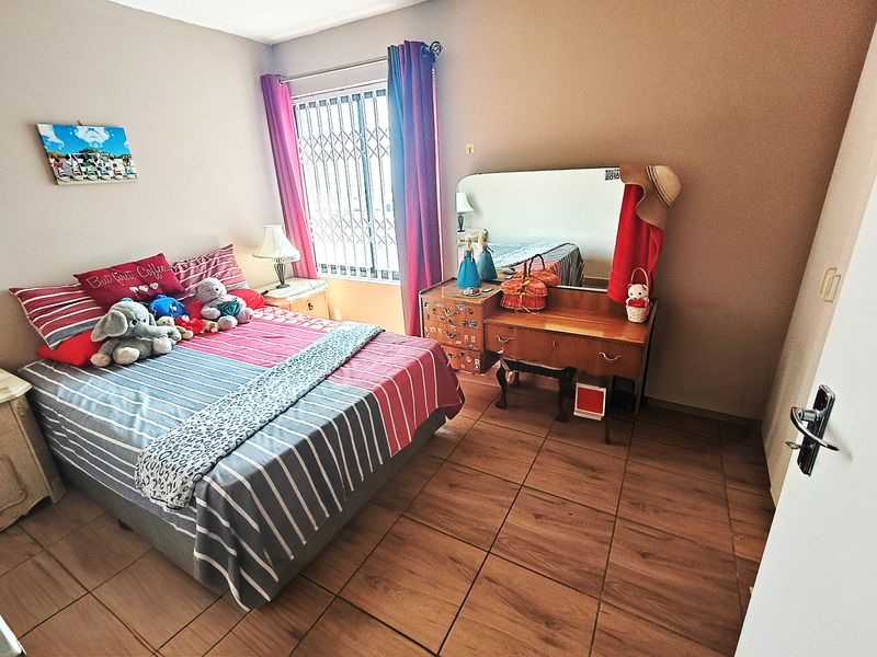 A bedroom featuring tiled flooring and a window fitted with a security gate.