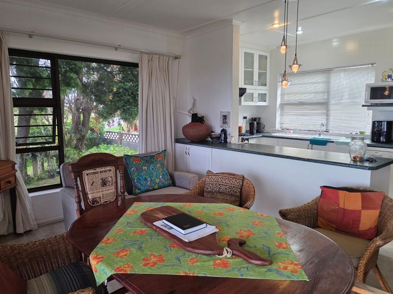 Open plan living and kitchen area featuring a breakfast bar, functional cabinetry, and large sliding doors providing natural light and garden views.
