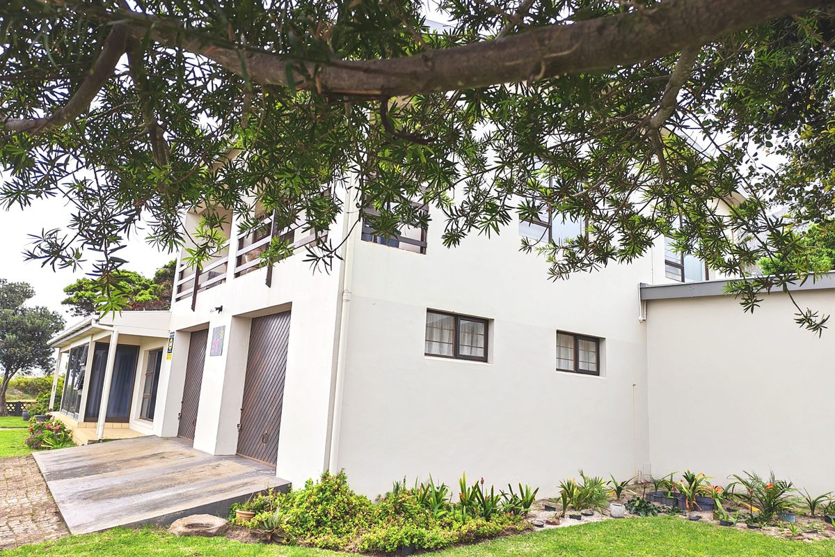 Rear view of the property featuring a double garage, an upper-level balcony, and a well-maintained garden area.