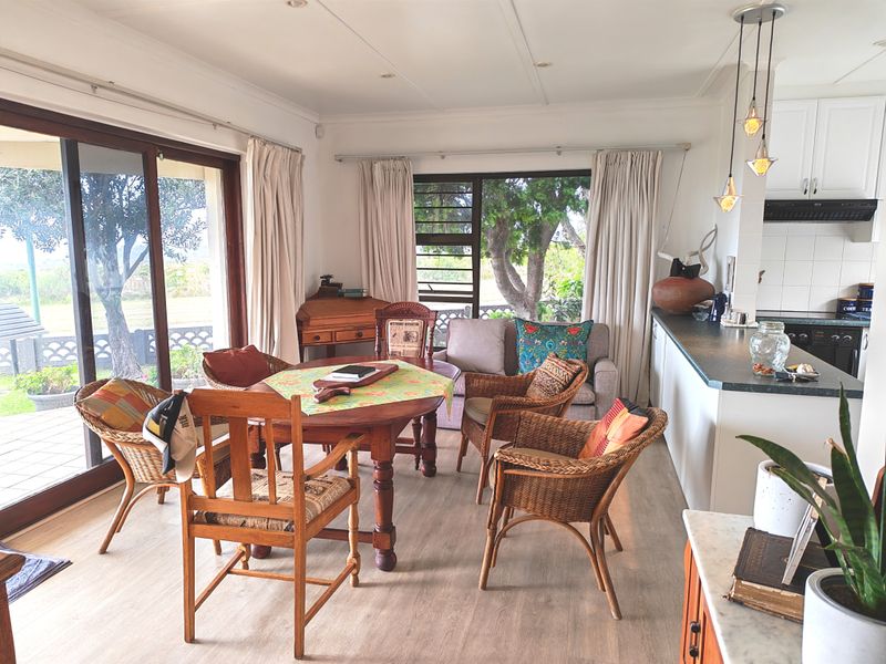 Open-plan living and dining area featuring a functional kitchen with island, ample natural light, and direct access to the outdoor patio through sliding doors.