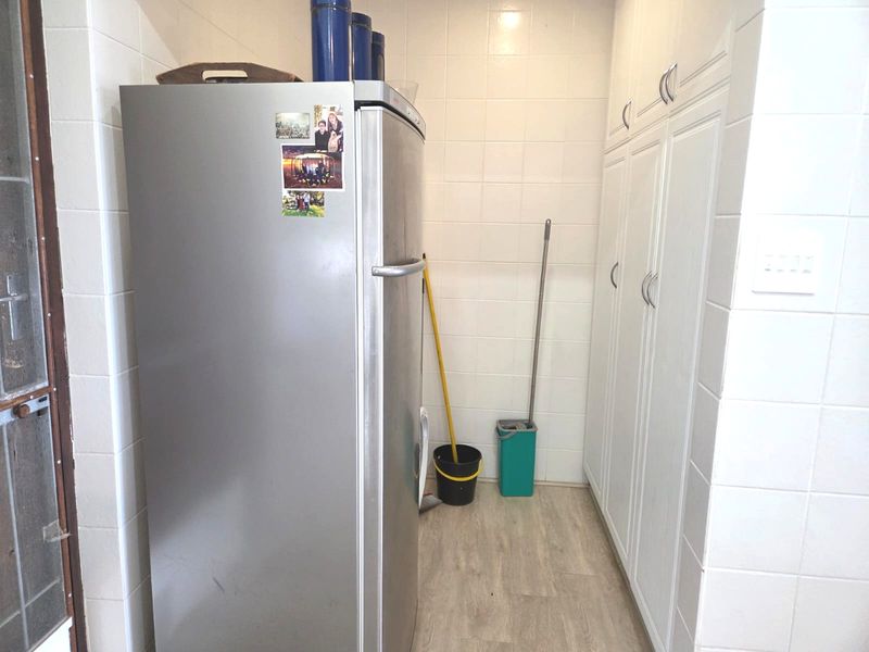 A functional laundry or utility space featuring white tiled walls, laminate flooring, and ample built-in storage cabinetry.