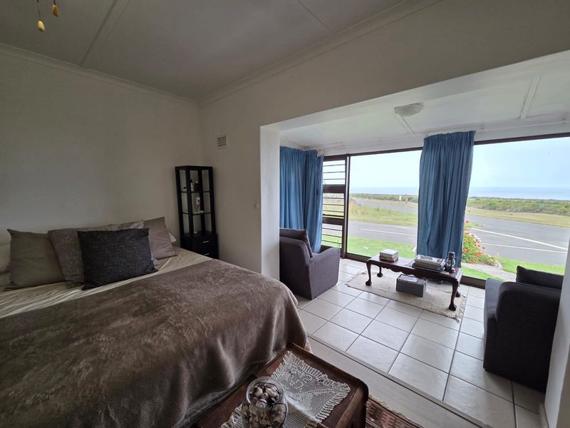 A bedroom featuring tiled flooring and large glass sliding doors that provide expansive views of the surrounding landscape.