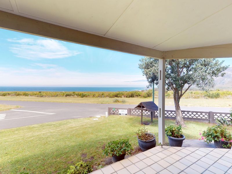 A covered patio area featuring tiled flooring and an open outlook towards the coastal landscape and ocean.