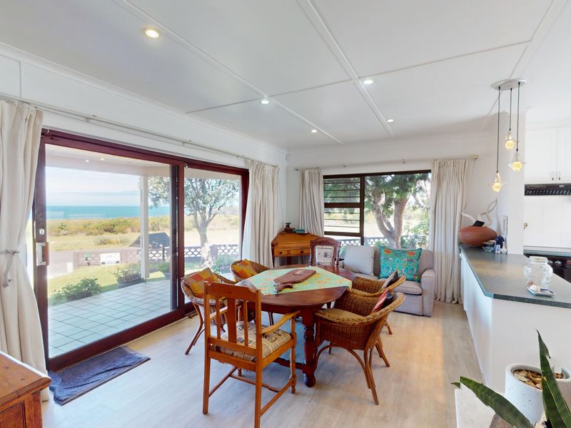 Open-plan living and dining area featuring large sliding doors with ocean views, integrated kitchen cabinetry, and modern recessed lighting.