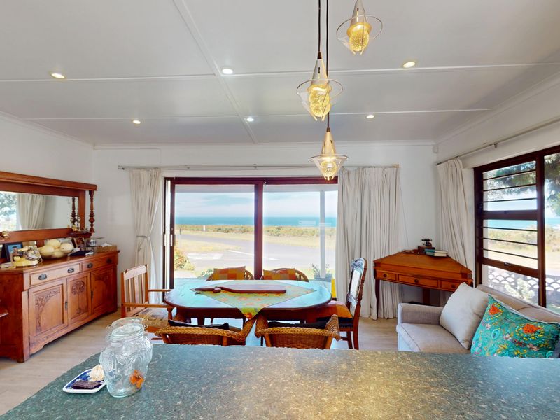 Open-plan living and dining area featuring tiled floors, recessed lighting, and large sliding glass doors that offer expansive coastal views.