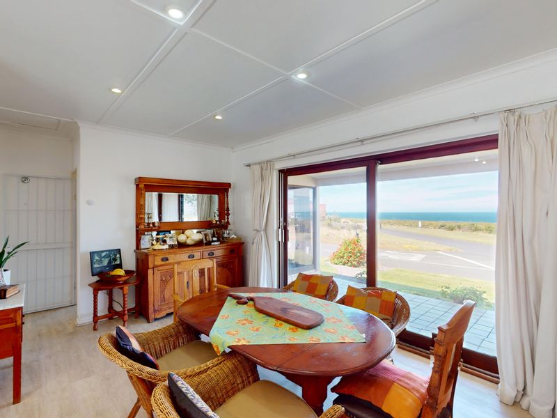 Bright dining area featuring tiled flooring, recessed lighting, and large sliding glass doors offering scenic coastal views.