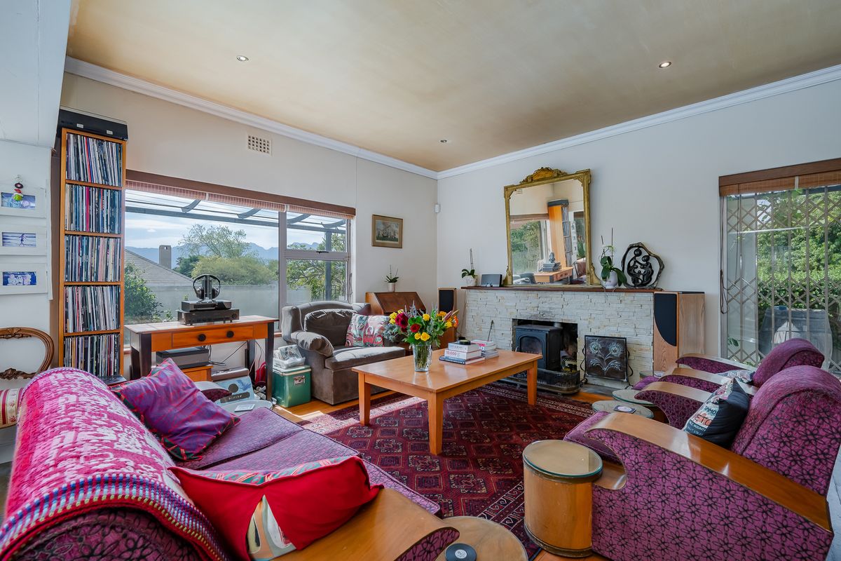 A spacious living room featuring a stone fireplace, recessed lighting, and large windows providing natural light and access to the outdoor area.