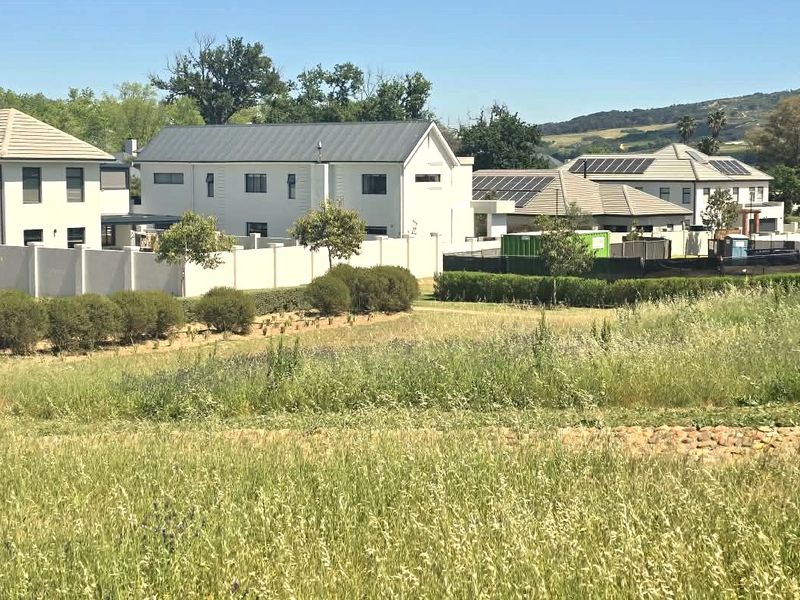 A view of the vacant residential land showing the surrounding established neighborhood, perimeter walls, and landscaped garden areas.
