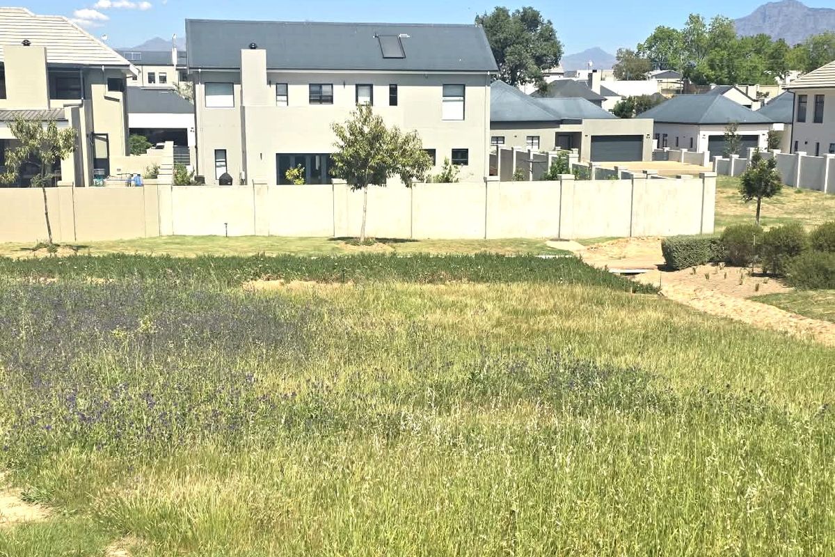 A view of a vacant residential plot featuring established perimeter walls and surrounding residential development.