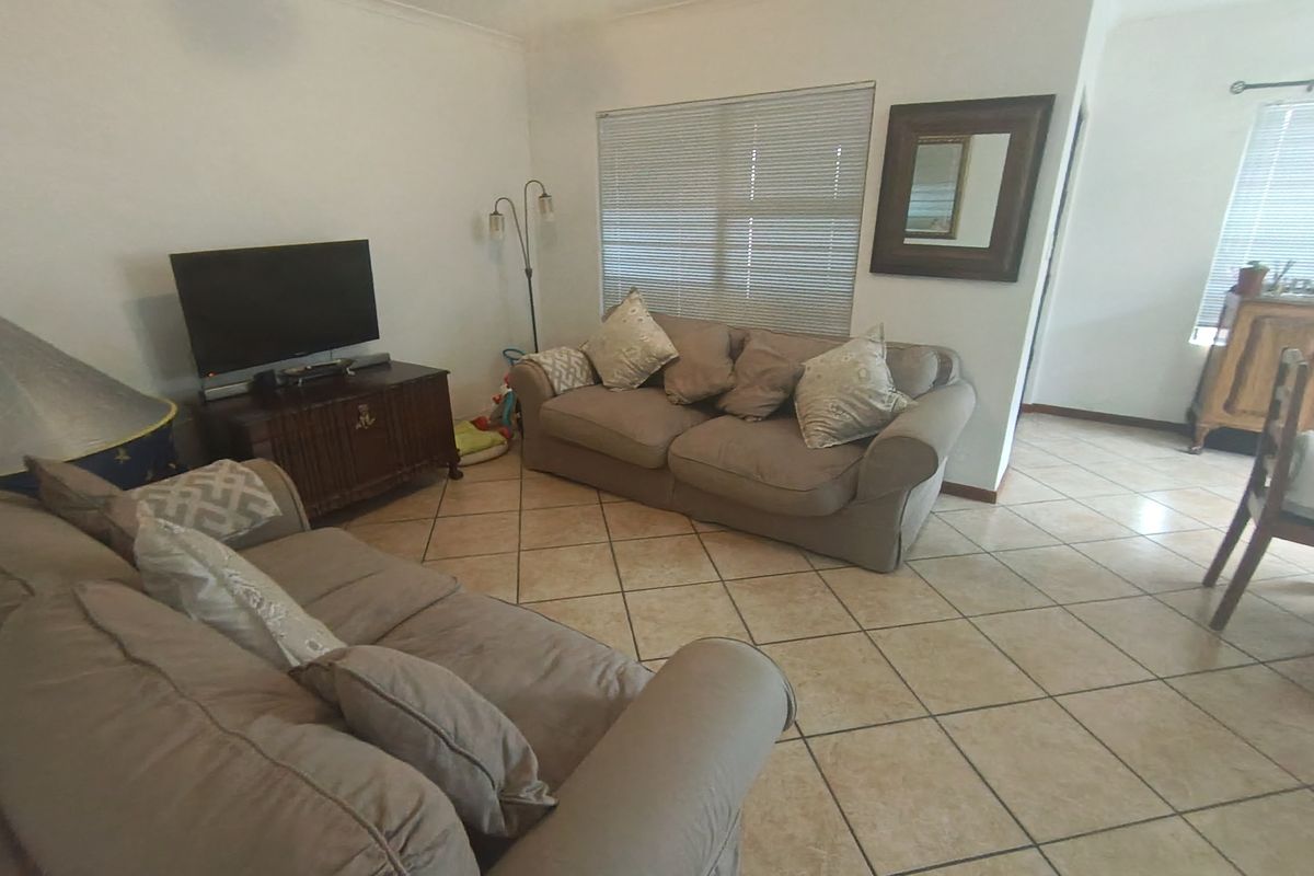 A living room featuring ceramic floor tiles and venetian blinds, offering a functional and neutral space for relaxation.