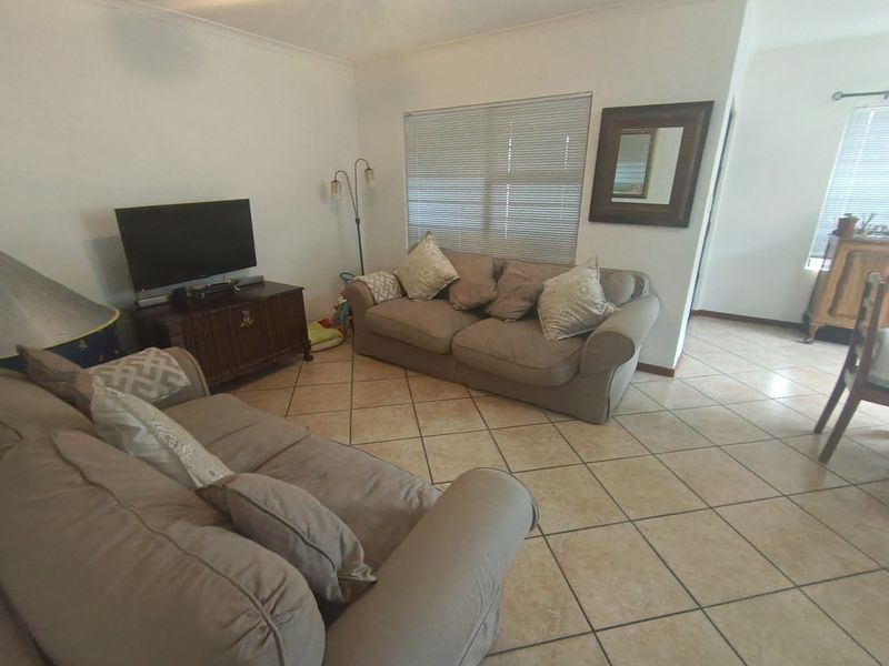 A living room featuring ceramic floor tiles and venetian blinds, offering a functional and neutral space for relaxation.