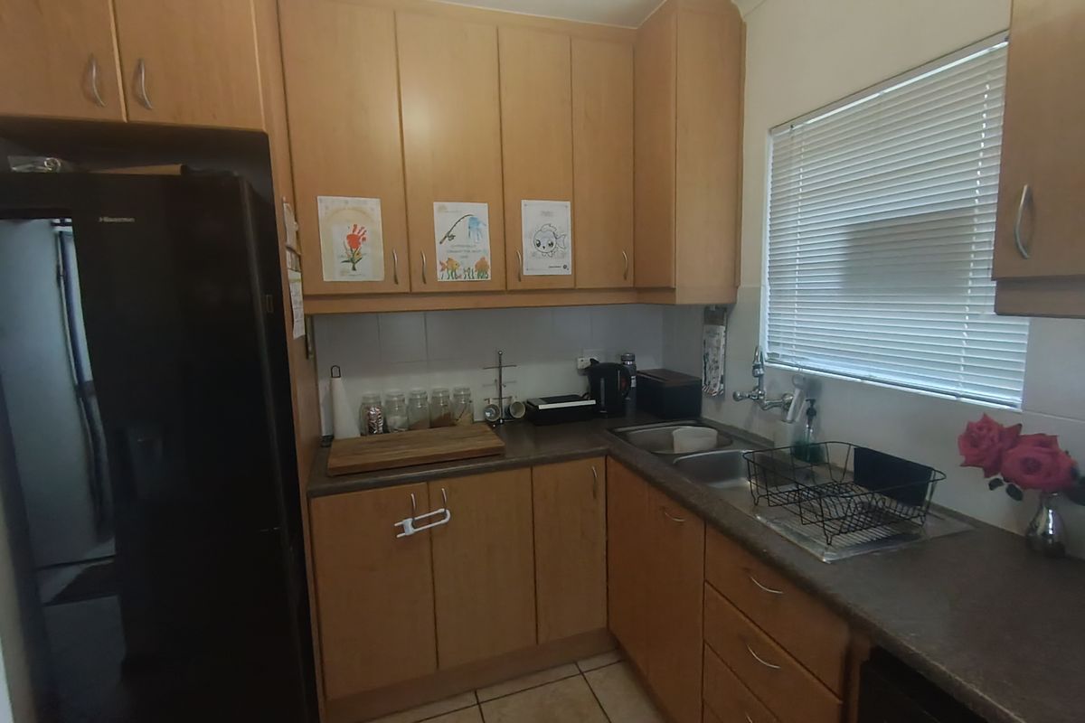 A functional kitchen featuring laminate cabinetry, laminate countertops, a double bowl stainless steel sink, and tiled flooring.
