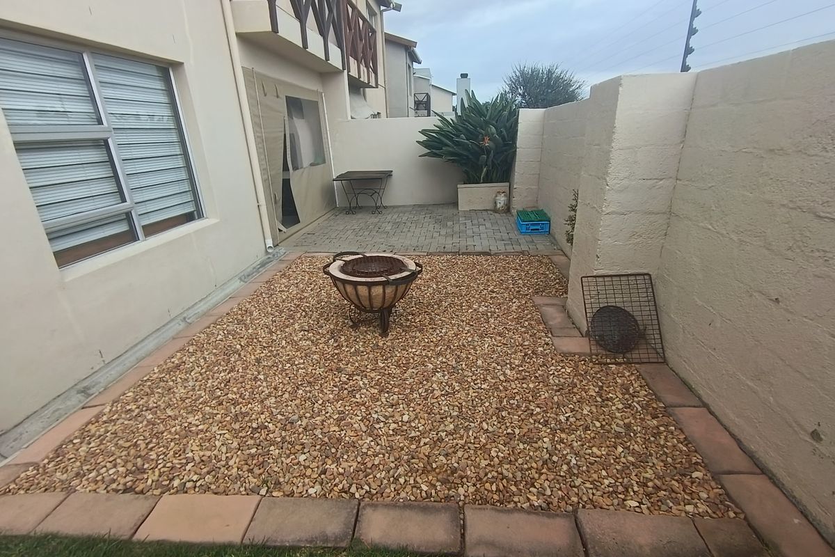 A private rear courtyard featuring a paved patio area, gravel garden section, and secure boundary walls with electric fencing.