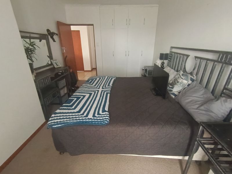 A bedroom featuring built-in cupboards and carpeted flooring, providing a functional space with direct access to the hallway.