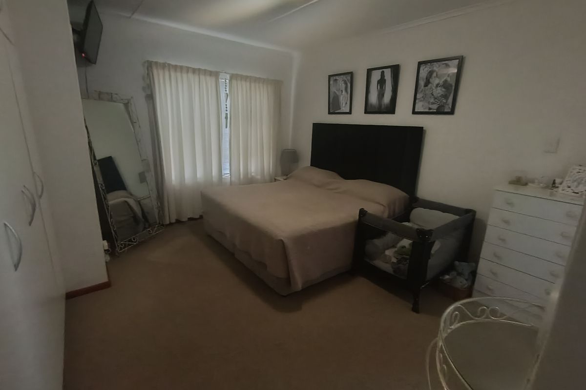 A standard bedroom featuring built-in cupboards and carpeted flooring, providing a functional space with neutral finishes.