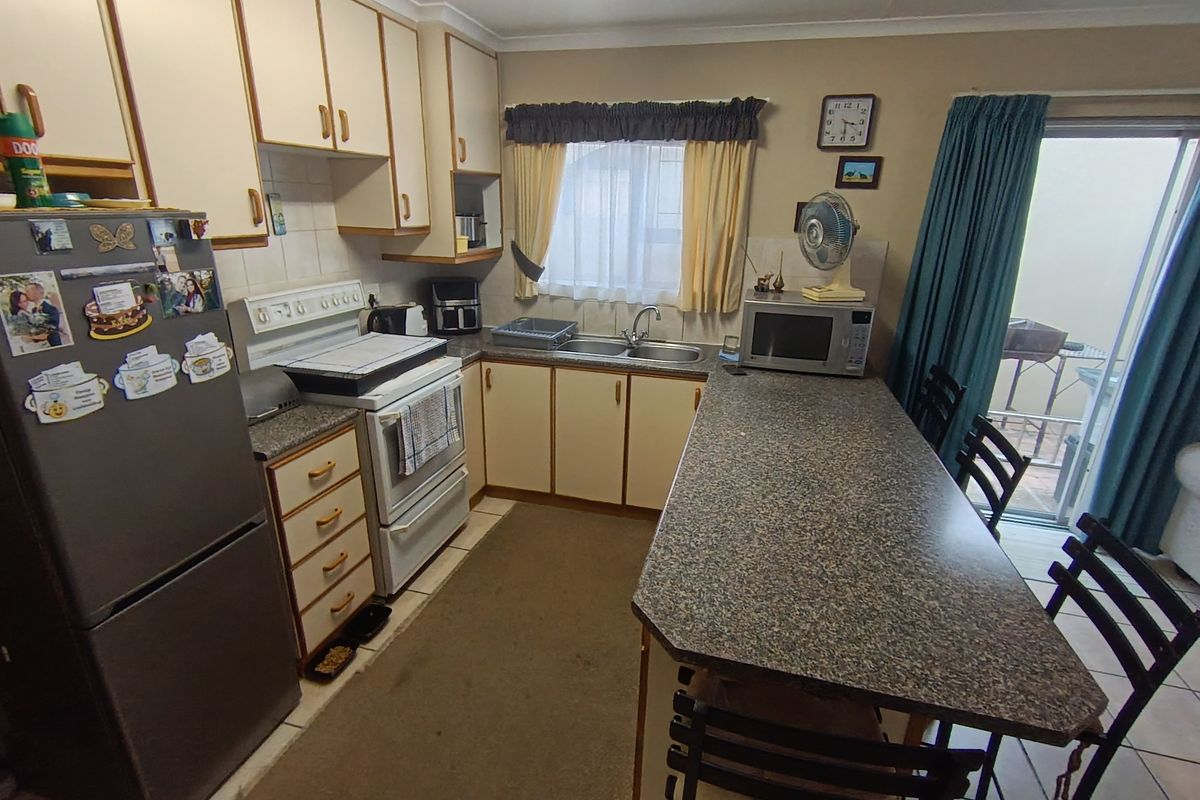 A functional kitchen featuring laminate cabinetry, granite-look countertops, a breakfast bar, and direct access to an outdoor area through a sliding glass door.