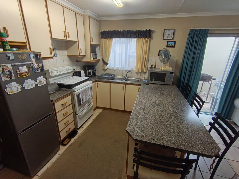 A functional kitchen featuring laminate cabinetry, granite-look countertops, a breakfast bar, and direct access to an outdoor area through a sliding glass door.