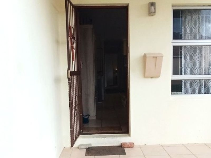 Front entrance of the townhouse featuring a security gate, tiled porch area, and a wall-mounted mailbox.