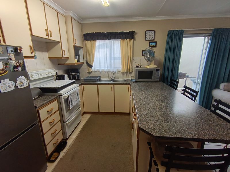 A functional kitchen featuring laminate countertops, built-in cabinetry, a breakfast bar, and a freestanding stove, with direct access to the outdoor patio area.