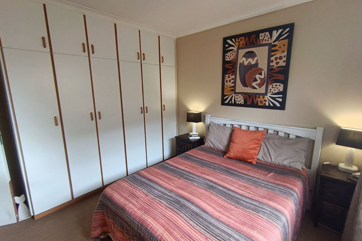 A well-maintained bedroom featuring extensive built-in cupboards and neutral carpeting, offering practical storage and a comfortable living space.