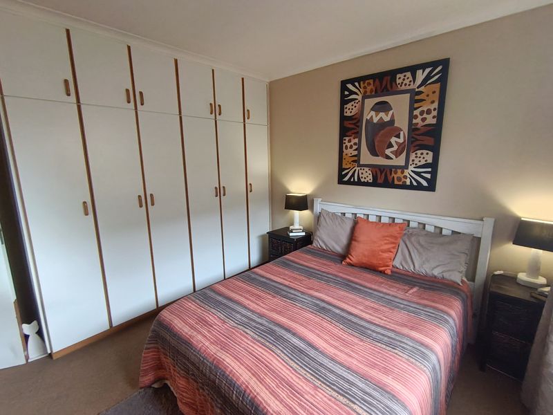 A well-maintained bedroom featuring extensive built-in cupboards and neutral carpeting, offering practical storage and a comfortable living space.