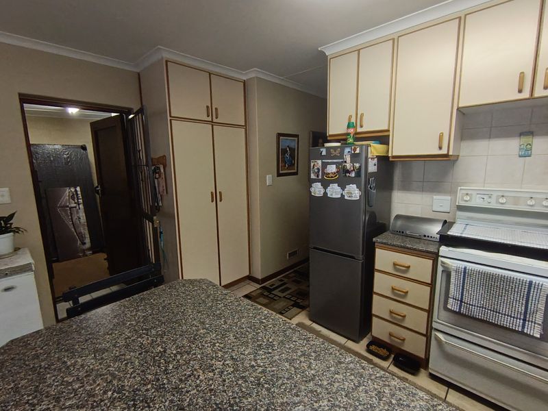 A functional kitchen featuring laminate countertops, built-in cabinetry, and a freestanding stove, offering a practical layout with potential for modern updates.