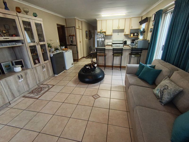Open-plan living and kitchen area featuring tiled flooring, a breakfast bar, and built-in cabinetry, providing a functional and connected living space.