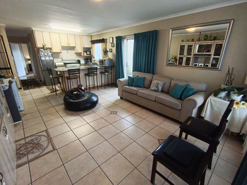 Open-plan living area featuring tiled flooring, a functional kitchen with built-in cabinetry and island, and direct access to the outdoors via sliding glass doors.