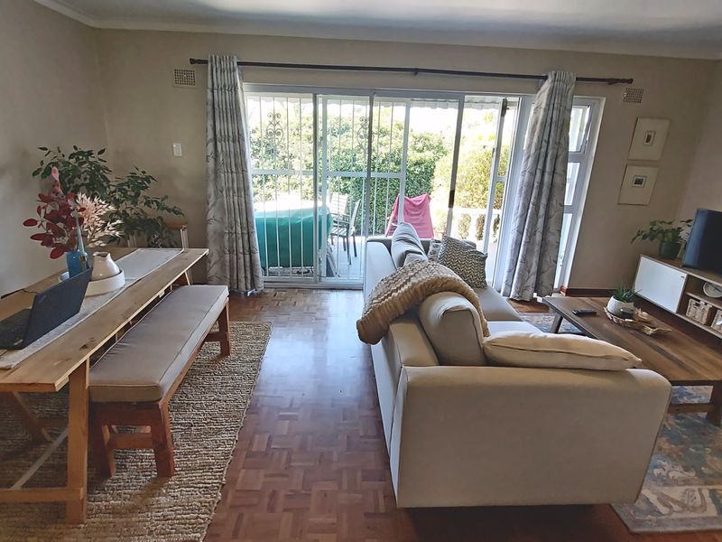 Spacious living area featuring classic parquet flooring and large sliding glass doors that provide direct access to the outdoor patio area.