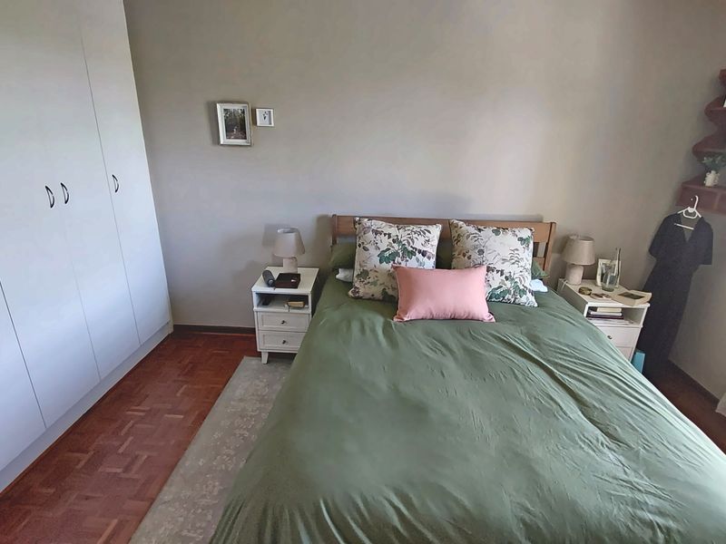 A cozy bedroom featuring classic parquet flooring and ample built-in cupboard storage, offering a functional and comfortable living space.