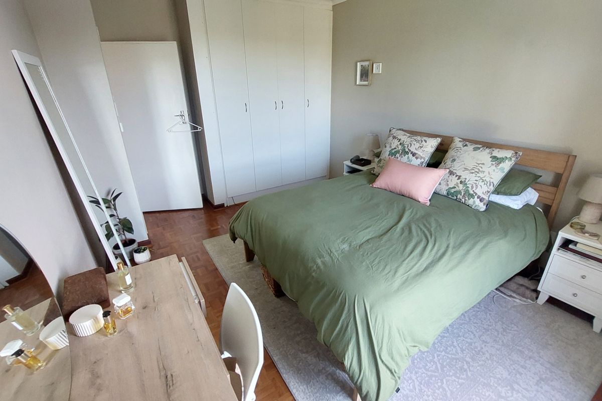A well-maintained bedroom featuring classic parquet flooring and ample built-in cupboard storage space.