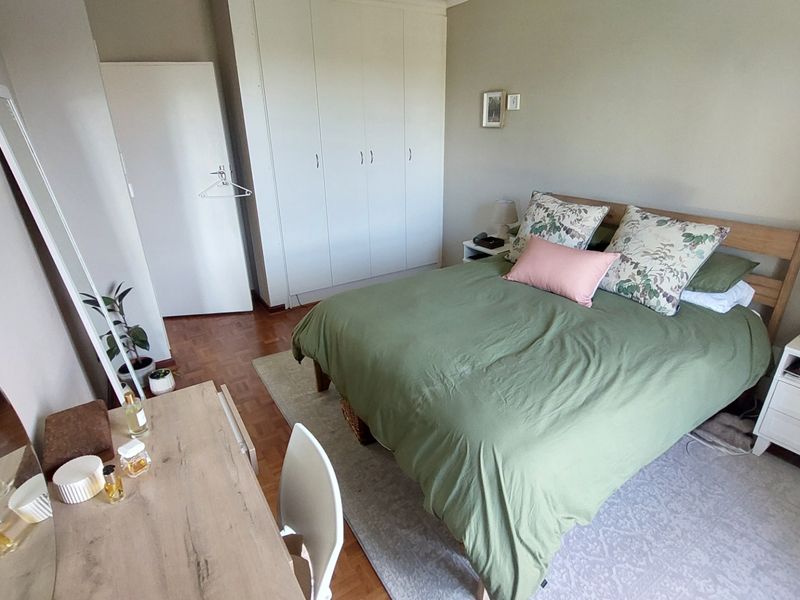 A well-maintained bedroom featuring classic parquet flooring and ample built-in cupboard storage space.