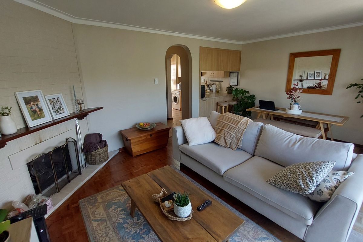 A comfortable living room featuring a brick fireplace, parquet flooring, and an arched doorway leading to the kitchen area.