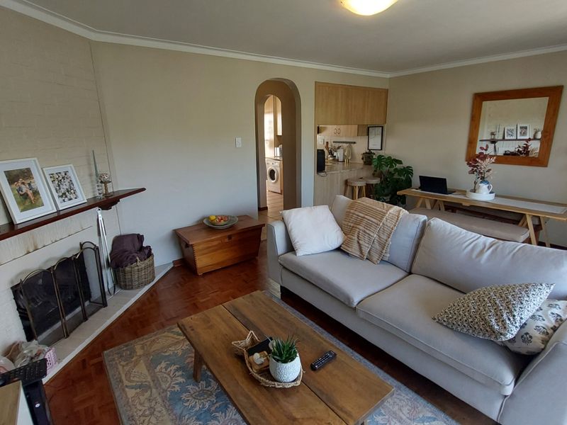 A comfortable living room featuring a brick fireplace, parquet flooring, and an arched doorway leading to the kitchen area.