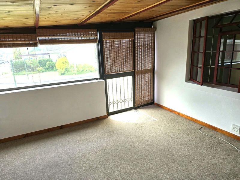 An enclosed patio area featuring a timber tongue and groove ceiling, carpeted flooring, and large windows providing natural light.