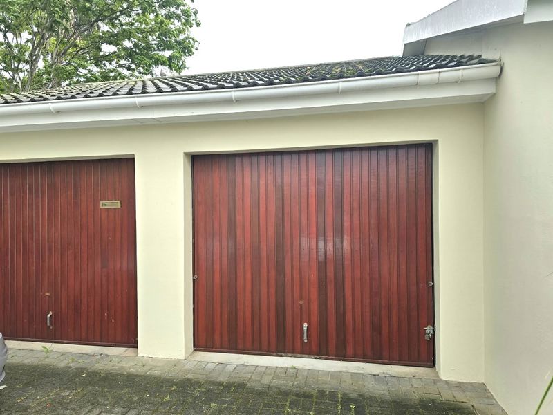 Exterior view of a double garage featuring timber-style doors, tiled roofing, and paved driveway access.