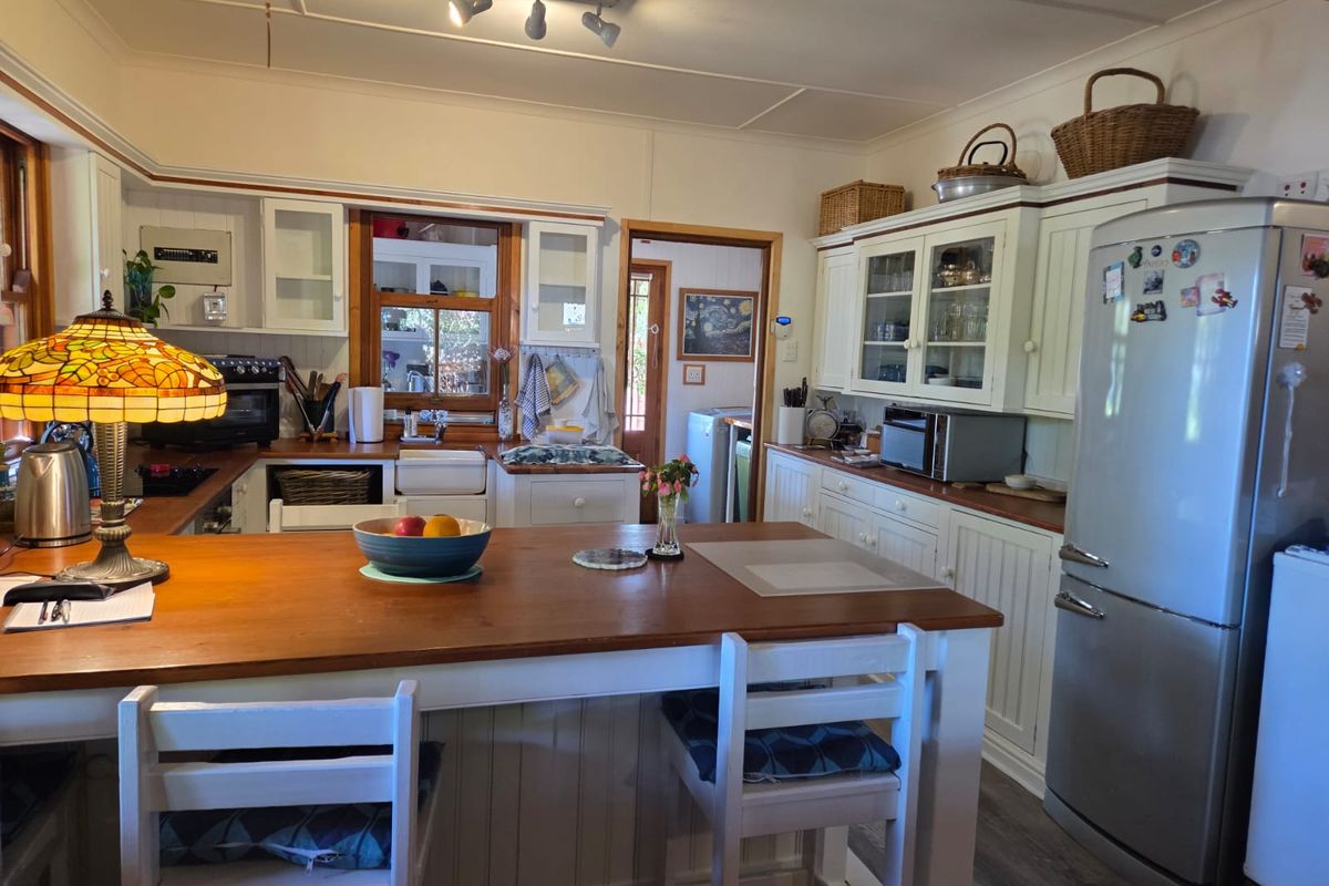A charming country-style kitchen featuring timber countertops, a farmhouse sink, and ample built-in cabinetry with a central island for casual dining.