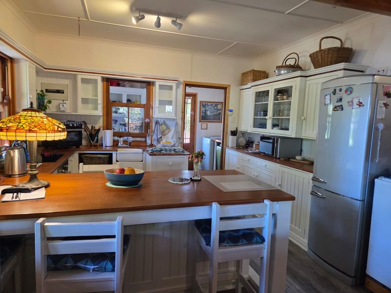 A charming country-style kitchen featuring timber countertops, a farmhouse sink, and ample built-in cabinetry with a central island for casual dining.