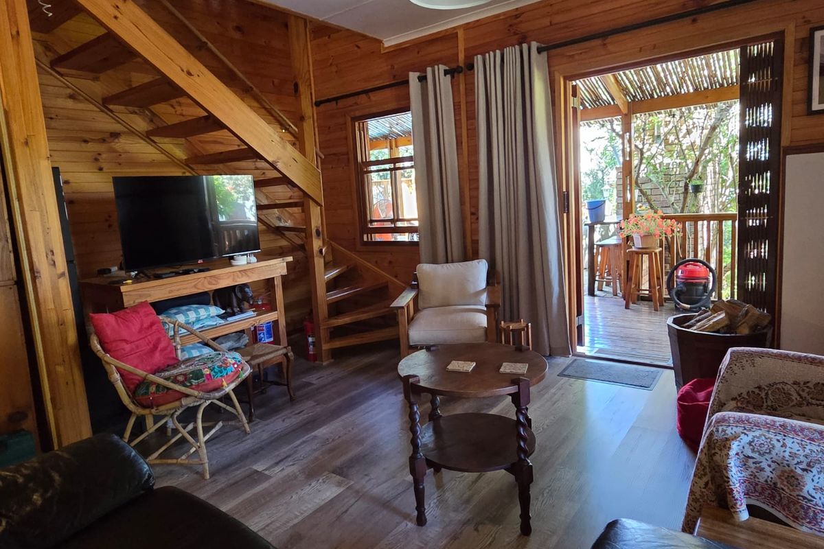 Cozy living room featuring warm timber wall cladding, wooden flooring, and a staircase, with direct access to an outdoor patio area.
