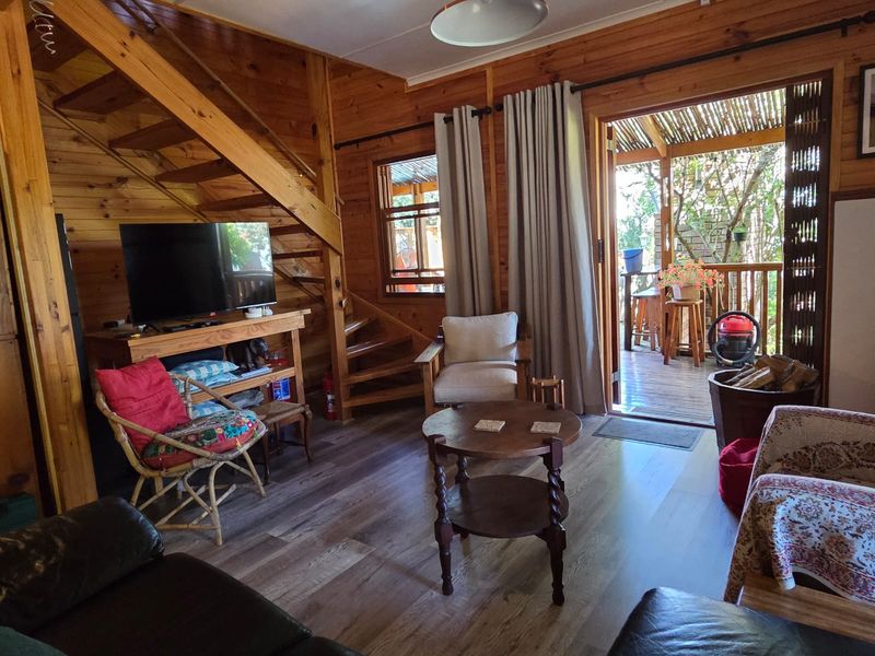 Cozy living room featuring warm timber wall cladding, wooden flooring, and a staircase, with direct access to an outdoor patio area.
