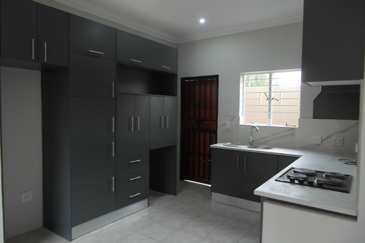 Modern kitchen featuring dark grey cabinetry, stone-look countertops, a built-in gas hob, and tiled flooring in a clean, well-lit space.