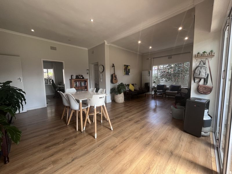 Spacious open-plan living and dining area featuring warm laminate flooring, recessed lighting, and large windows that provide ample natural light.