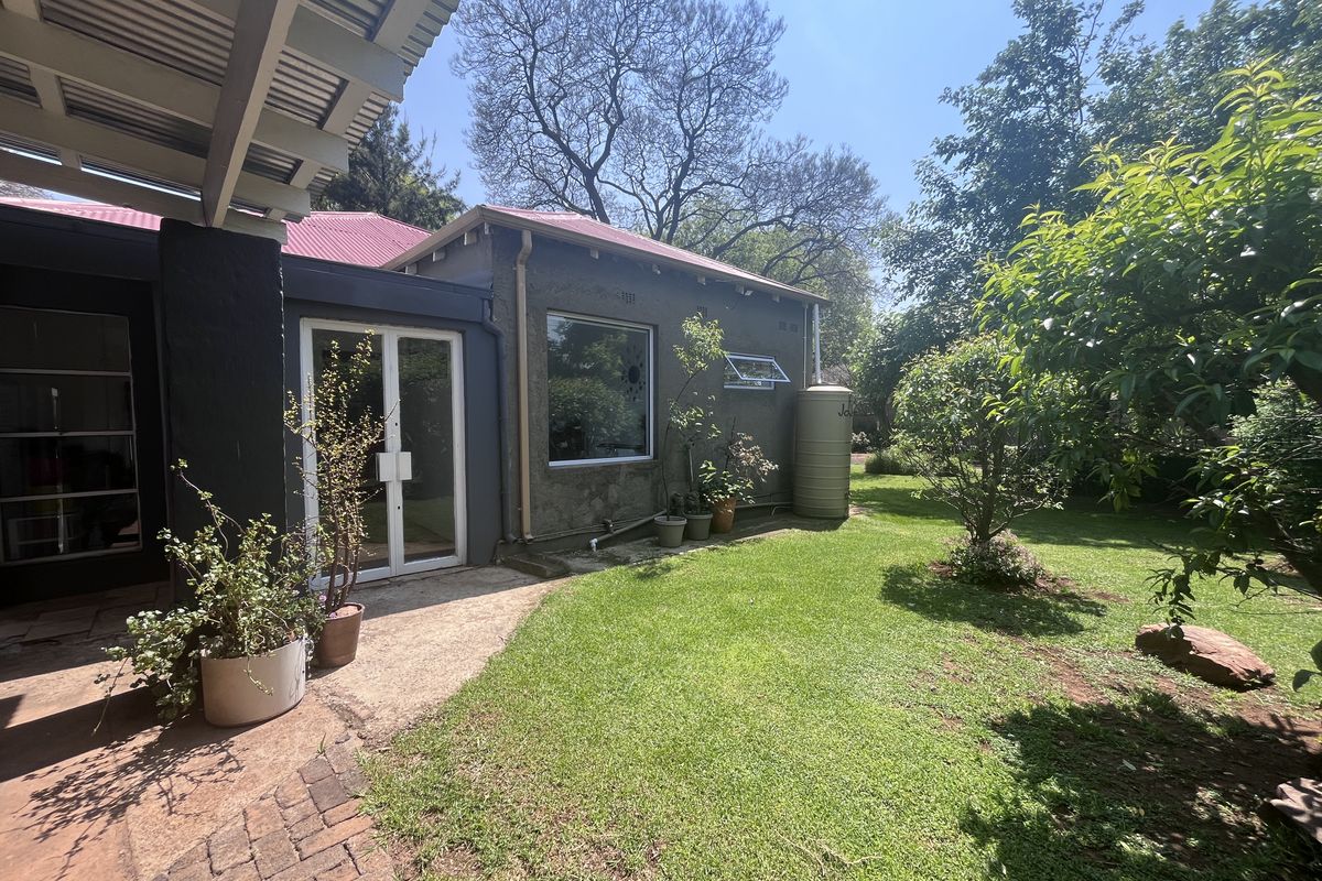 Rear view of the property featuring a covered patio, brick paving, a well-maintained lawn, and a water storage tank against the exterior wall.